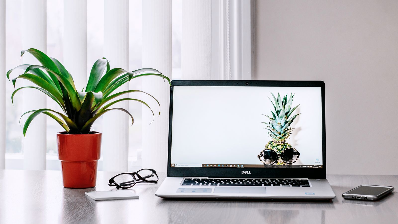 Mesa clara de consultório com smartphone e notebook, sem pessoas, em ambiente moderno
